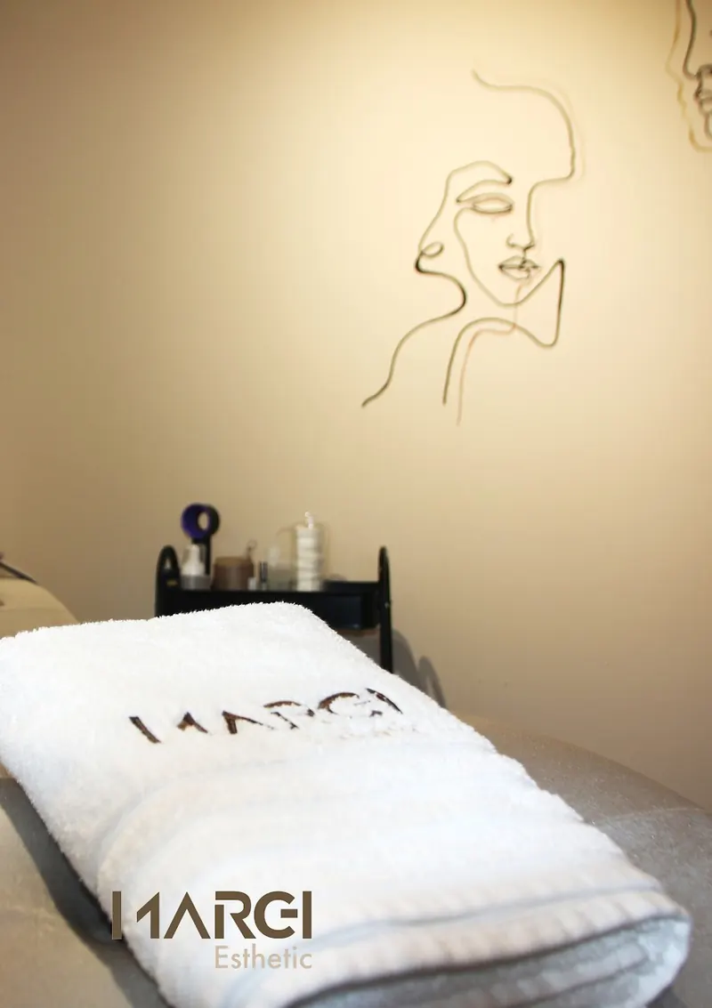 Treatment room with a Marei towel on the bed and line-art faces on the wall