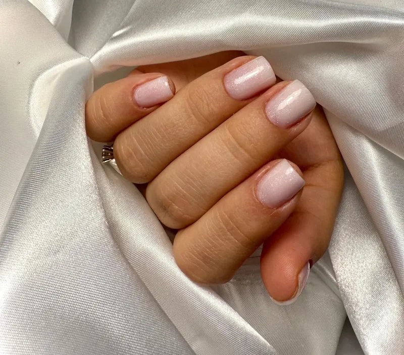 Shimmering pale pink nails in white satin