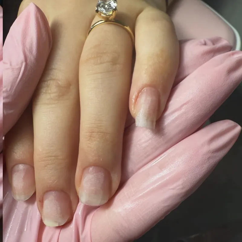 Natural gel manicure with a solitaire ring on a pink-gloved hand