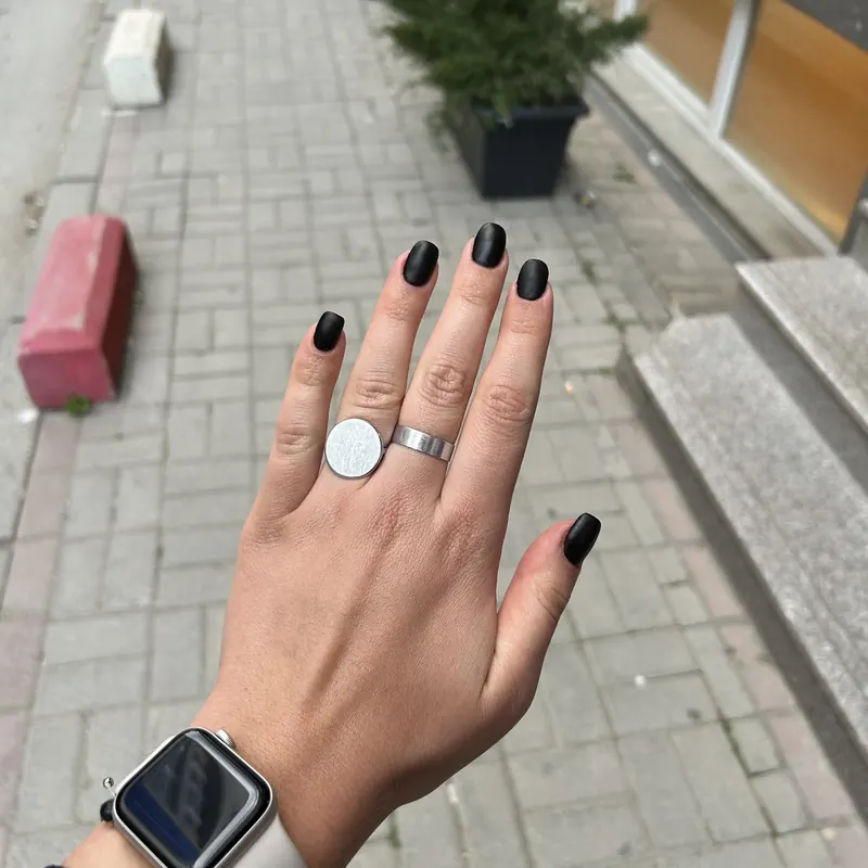 Glossy black manicure photographed on a Prishtina street